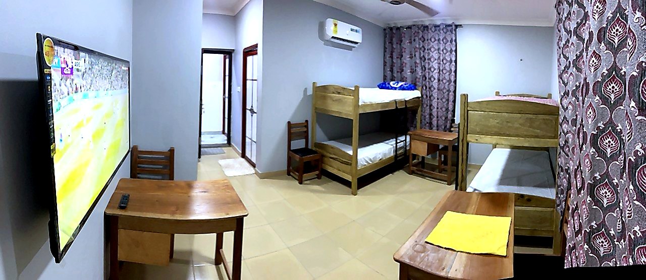 Bright shared student room with beds, desk, curtains, and air conditioning