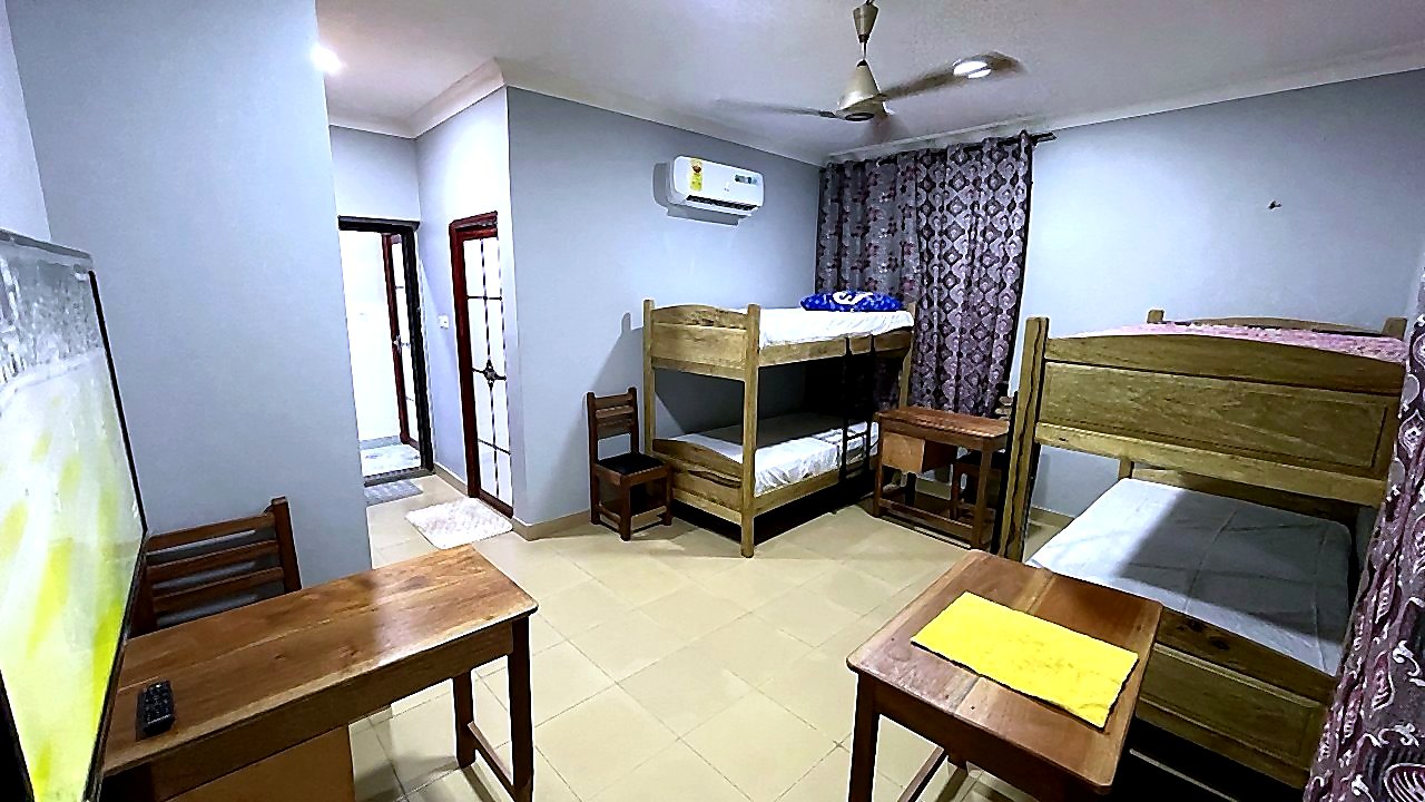 Four-bed student room with wooden bunk beds and study desks at Jeffston Court Hostel